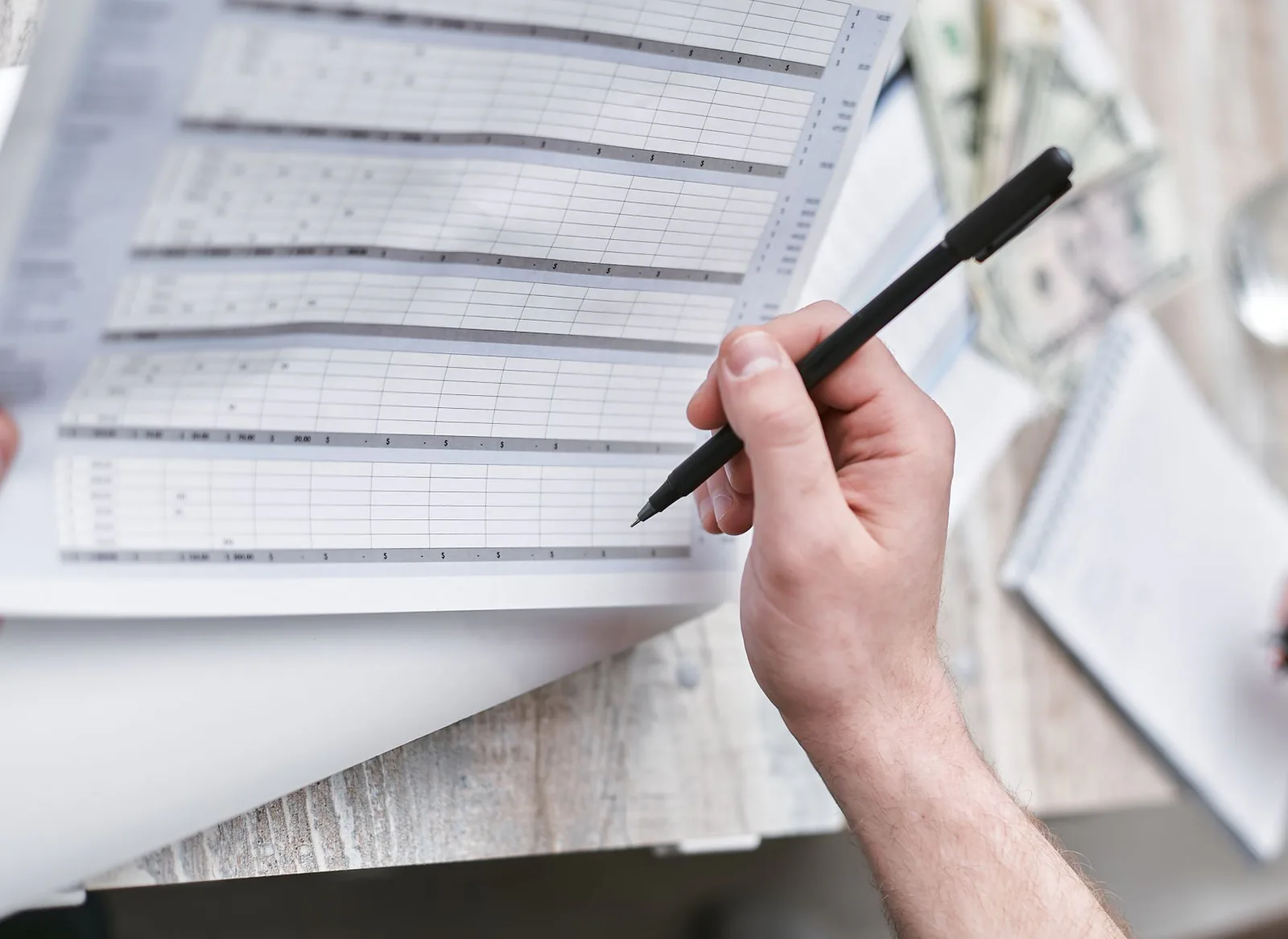 Hand annotating a printed financial table with a pencil to analyse a building's profitability