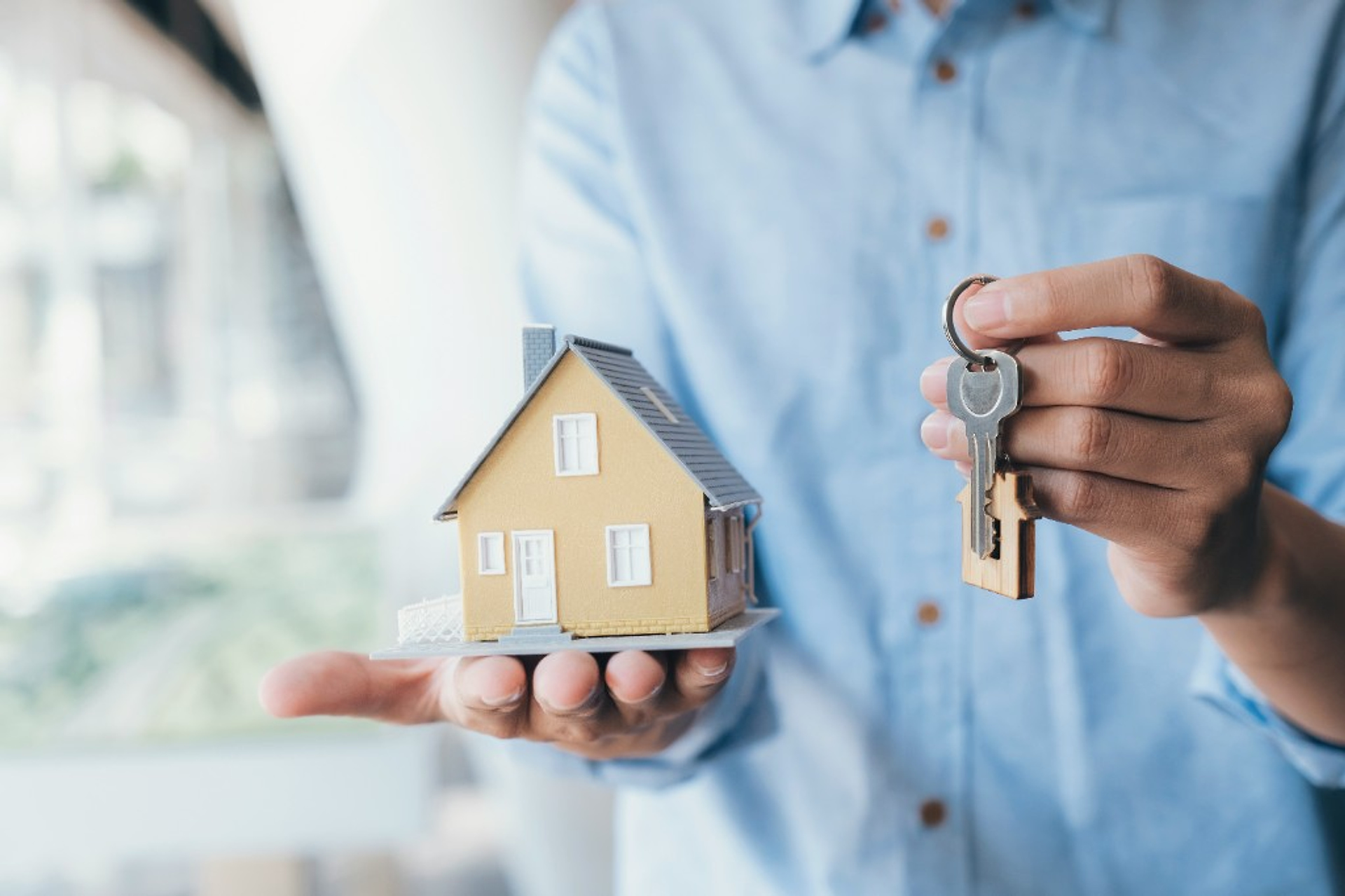 Person holding a miniature house and keys, avoiding mistakes when selling a home in Quebec.