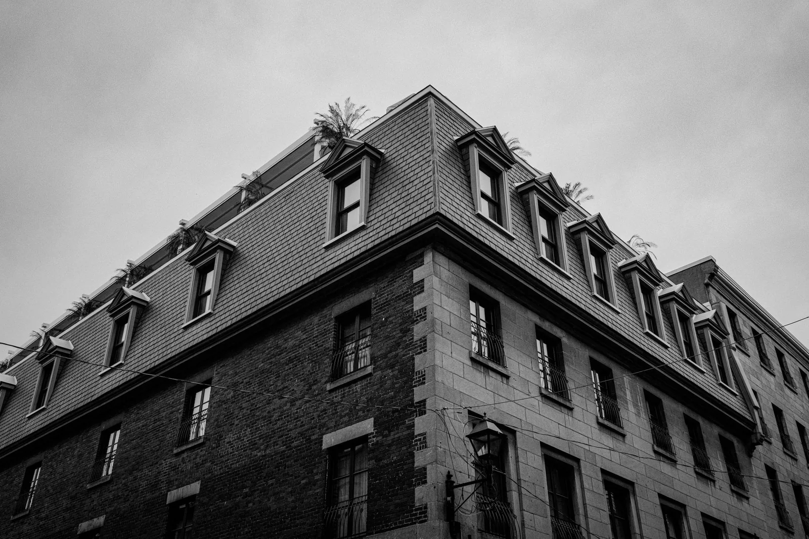 Older brick and stone building topped with a mansard roof, photographed from below