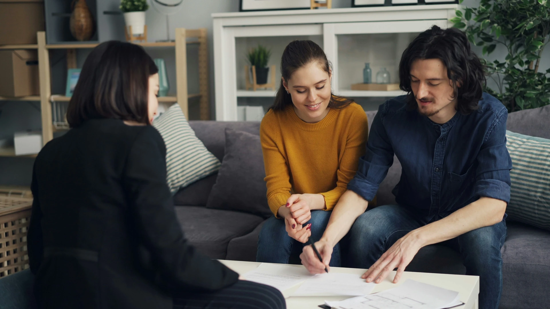 Couple remplissant des documents au salon avec un courtier immobilier à Saint-Jérôme lors d'une rencontre à domicile.